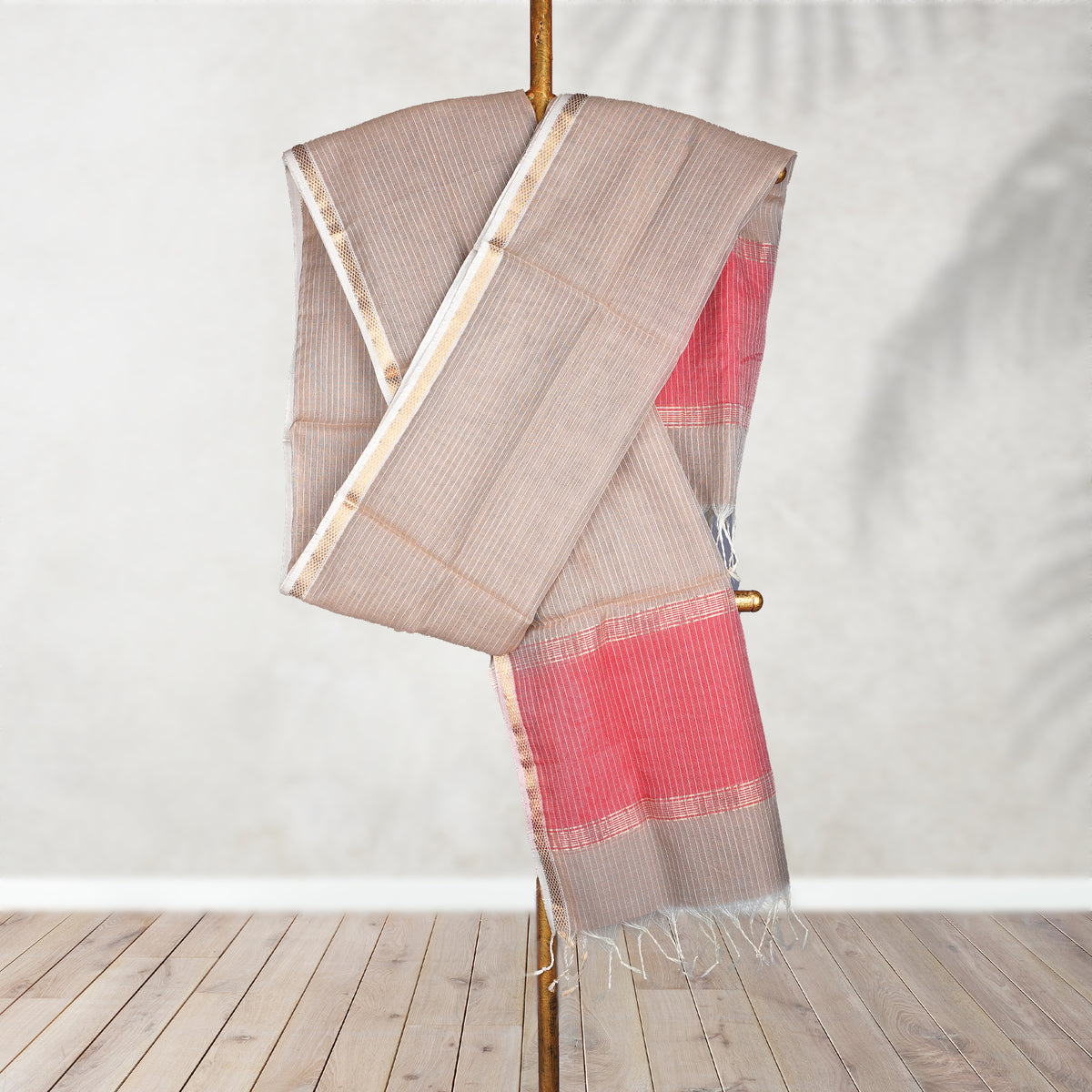Dupatta with pink and brown pattern on a wooden stand against a white wall.